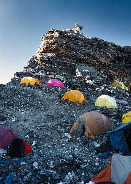 Zeltlager an steilem Berghang mit bunten Zelten und felsiger Umgebung.