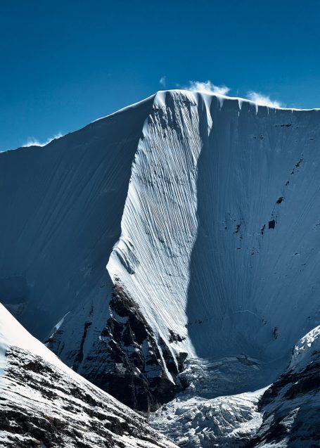Schneebedeckter Gipfel mit steilen Hängen und klarem blauem Himmel.