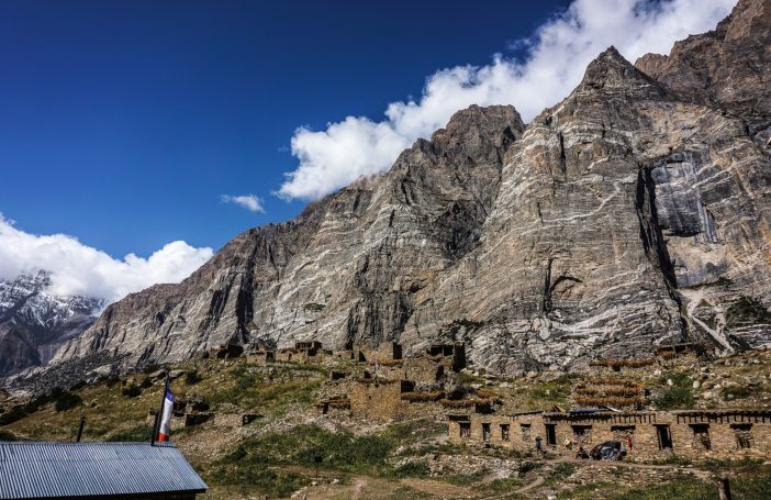 Berglandschaft mit steilen Felsen und historischen Ruinen im Vordergrund.