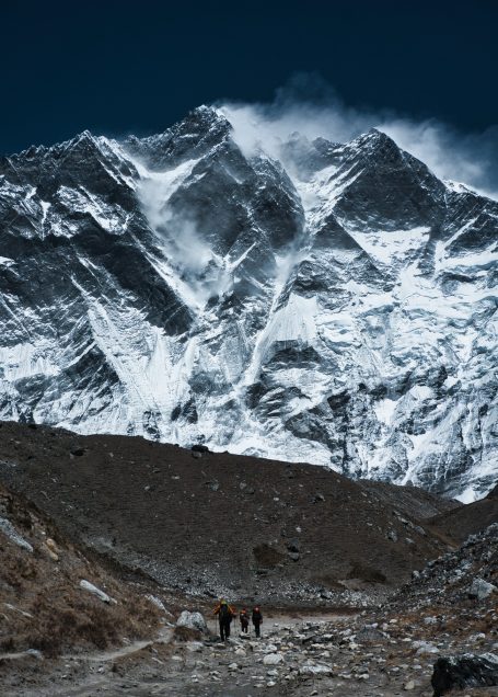Berglandschaft mit schneebedeckten Gipfeln und Wanderern im Vordergrund.