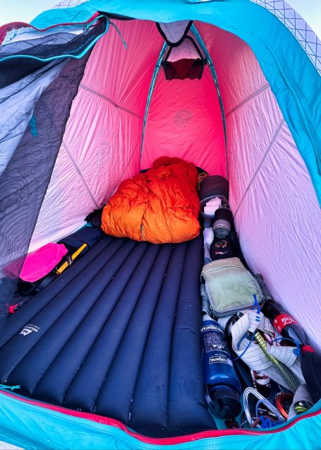 Zeltinnere mit Luftmatratze, Schlafsack und Campingausrüstung liegt auf dem Boden.