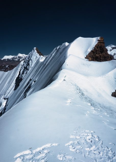 Berggipfel mit schneebedeckten Hängen und klarem, blauem Himmel.