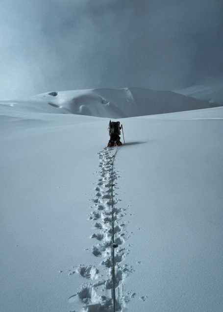 Schneebedeckte Landschaft mit einer Spur von Fußabdrücken zu einer kleinen Hütte.