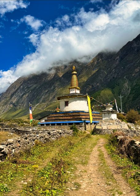 Buddhist Stupa in einer Berglandschaft mit Wolken und grünem Tal.