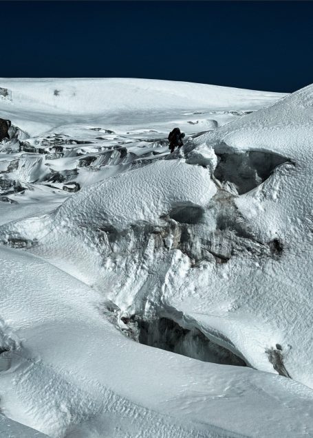 Schneebedeckte Landschaft mit sanften Hügeln und tiefblauem Himmel.