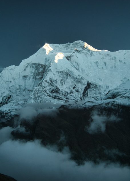 Hoher schneebedeckter Berggipfel unter einem klaren, dunklen Himmel.