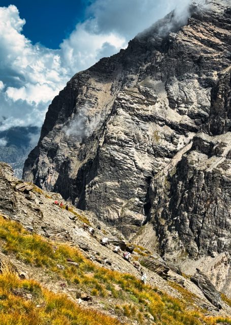 Felsige Berglandschaft mit grünem Vorland und dramatischem Wolkenhimmel.