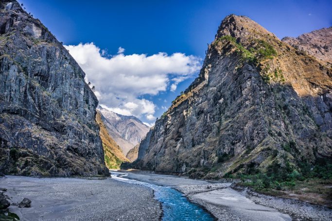 Berglandschaft mit steilen Klippen und einem klaren Fluss im Tal.