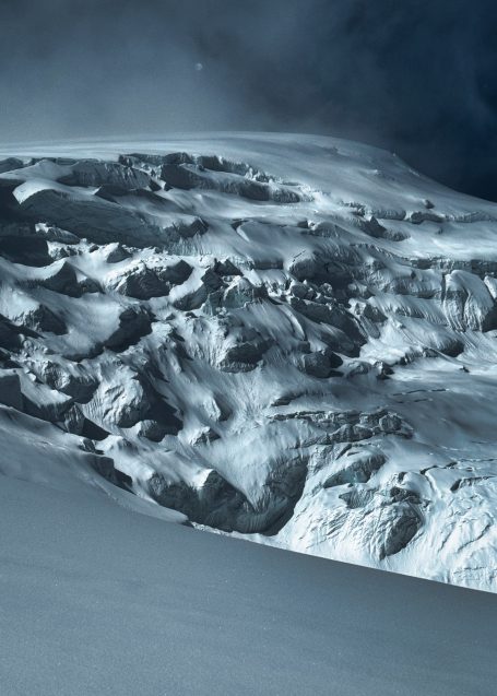 Verschneite Berglandschaft mit dramatischen Felsformationen und Schatten.