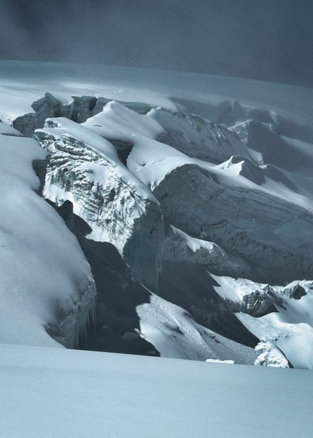 Schneebedeckte Berglandschaft mit zerklüftetem Gletscher und Felsen.