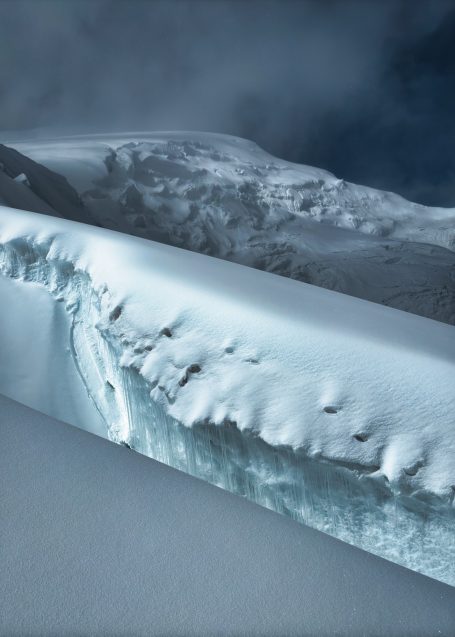Eisschicht mit spitzem Rand und verschneitem Berg im Hintergrund.