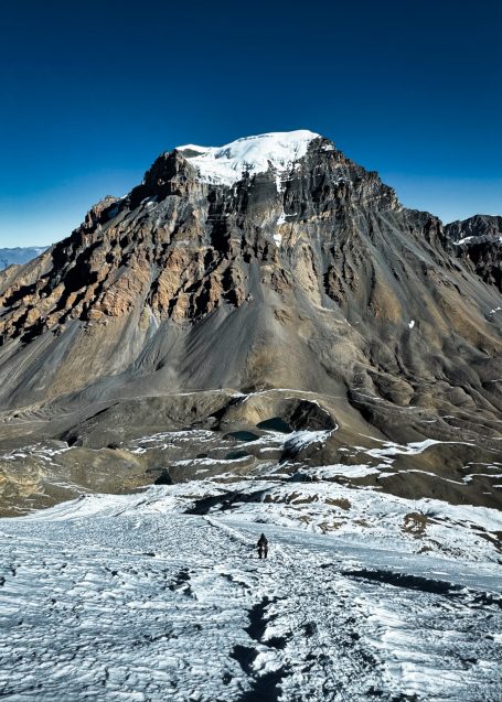 Hochgebirgslandschaft mit schneebedecktem Gipfel und steilen, felsigen Hängen.