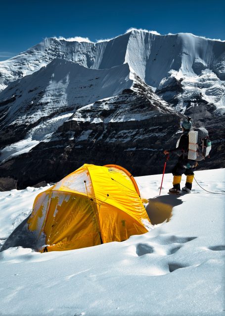Zelt aus gelbem Material in schneebedeckter Berglandschaft.