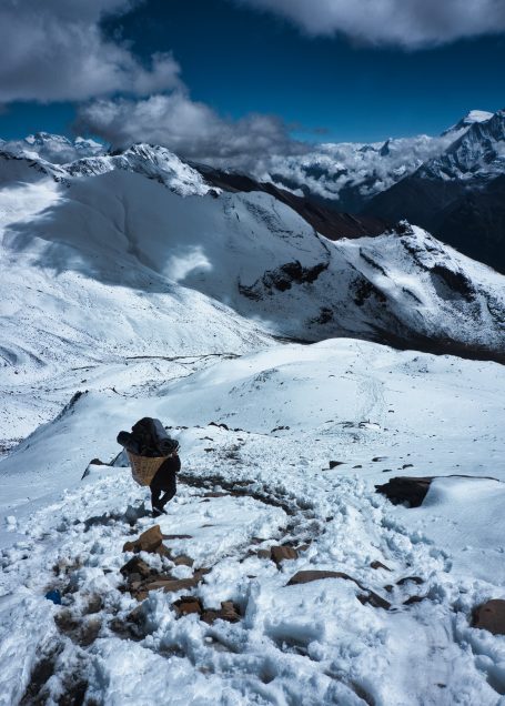 Ein Wanderer geht einen schneebedeckten Bergpfad mit imposanter Berglandschaft.