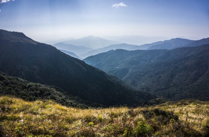 Aussicht auf hügelige Landschaften mit Bergketten und klarem Himmel.