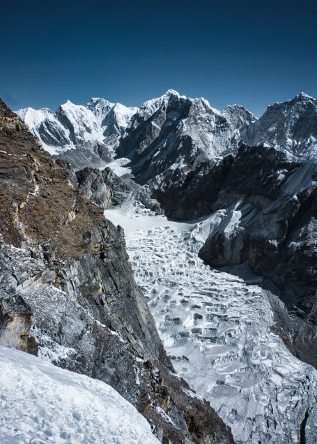 Schneebedeckte Berge mit einem großen Gletscher im Vordergrund unter klarem blauen Himmel.