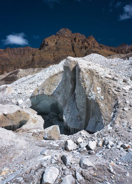 Helle felsige Landschaft mit tiefen Einschlüssen und einem bergigen Hintergrund.