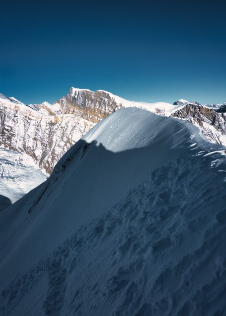 Schneebedeckter Berggipfel mit klaren blauen Himmel im Hintergrund.
