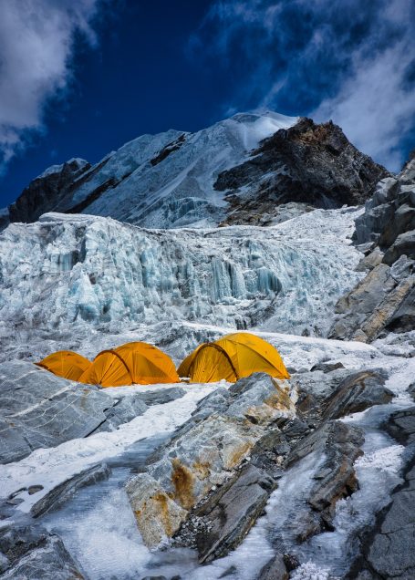 Zwei gelbe Zelte auf schneebedecktem Gelände unter einem blauen Himmel.