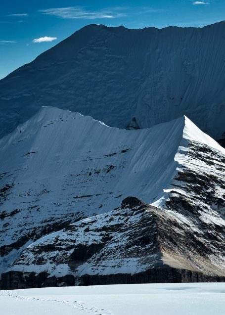 Schneebedeckte Berggipfel unter klarem, blauem Himmel in einer dramatischen Landschaft.