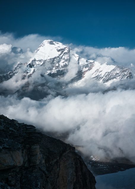 Hochgebirgslandschaft mit schneebedeckten Gipfeln und Wolken in der Nähe.