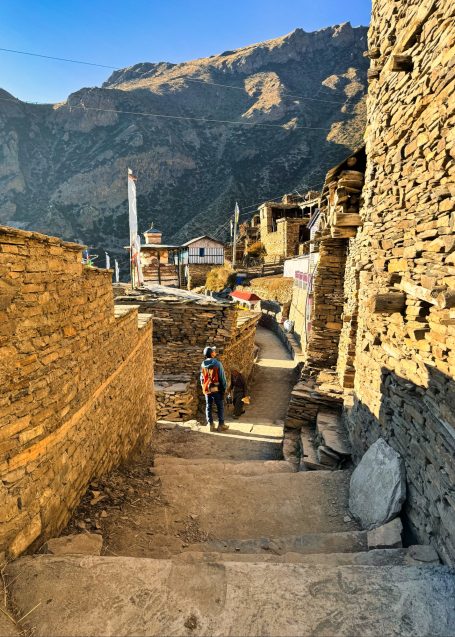Schmale steinerne Gasse in einem Bergdorf mit Blick auf die umliegenden Berge.