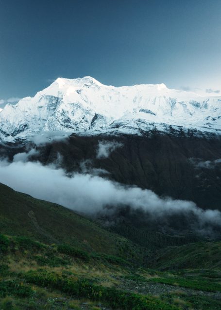 Schneebedeckter Gipfel über dem Nebel in einem gebirgigen Landschaftsbild.