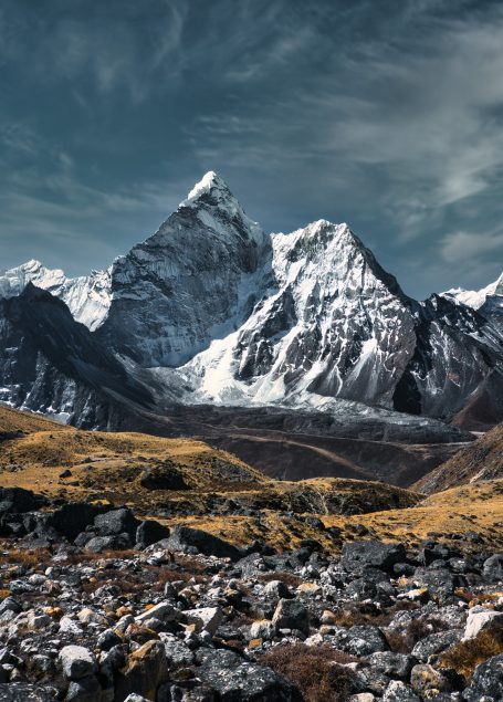 Schneebedeckte Berge mit steilen Felsen und bewölktem Himmel im Hintergrund.
