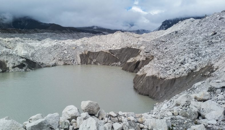 Berglandschaft mit grauen Felsen und stiller Wasserstelle in einer Senke.