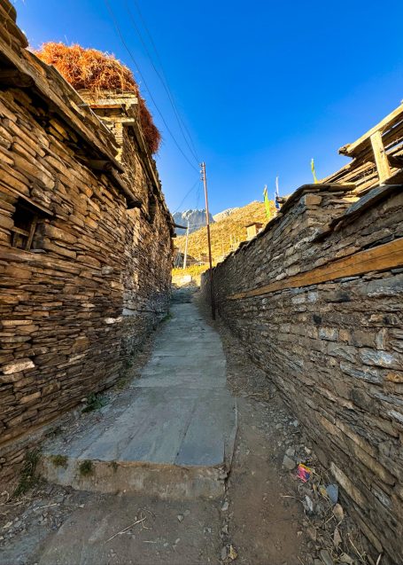 Schmale Gasse zwischen Holzhäusern, blaue Himmel im Hintergrund.