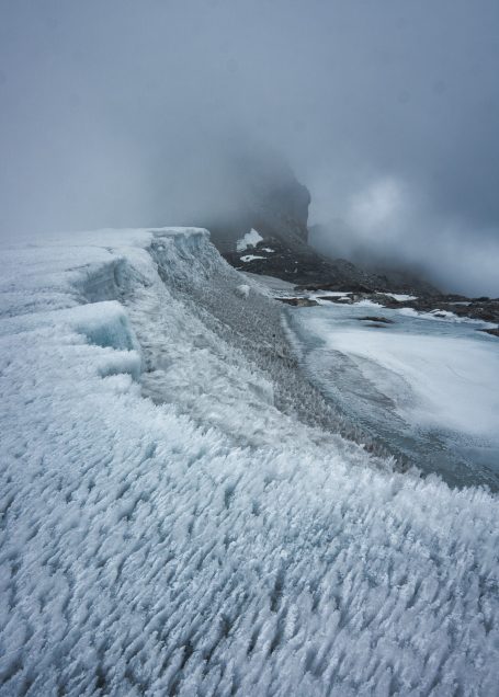 Eisige Landschaft mit schneebedecktem Terrain und nebligem Hintergrund.