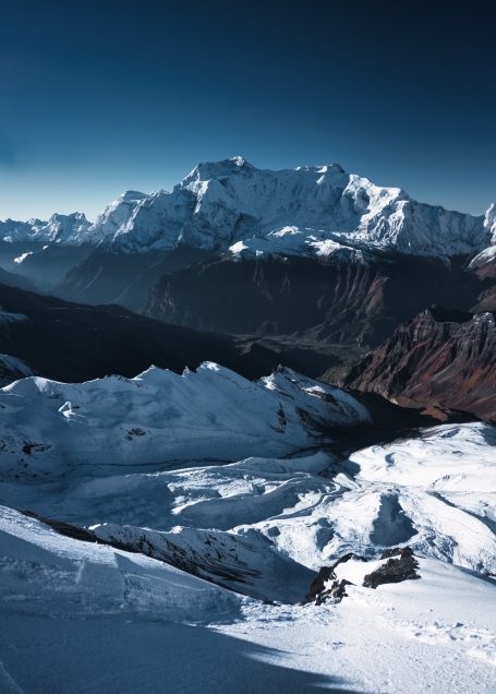 Schneebedeckte Berge unter klarem blauen Himmel, mit Licht- und Schatteneffekten.