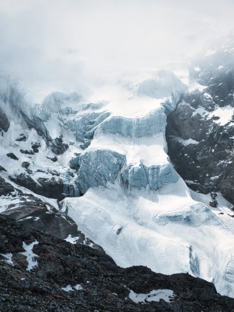 Gletscher mit schneebedeckten Felsen und Nebel im Hintergrund.