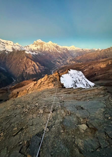 Berglandschaft mit schneebedeckten Gipfeln und steilen Hängen im warmen Licht der Morgensonne.