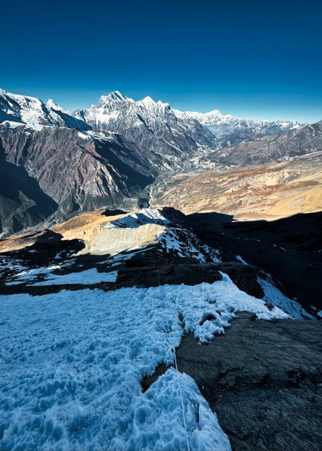 Schneebedeckte Berge und Täler unter klarem Blauhimmel, beeindruckende alpine Landschaft.