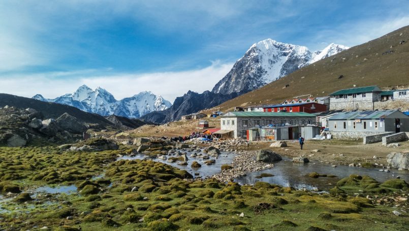 Alpenlandschaft mit schneebedeckten Bergen und einer kleinen Siedlung im Vordergrund.