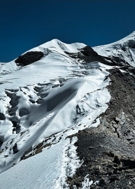 Schneebedeckte Berge unter klarem, blauem Himmel mit steilen Abhängen.