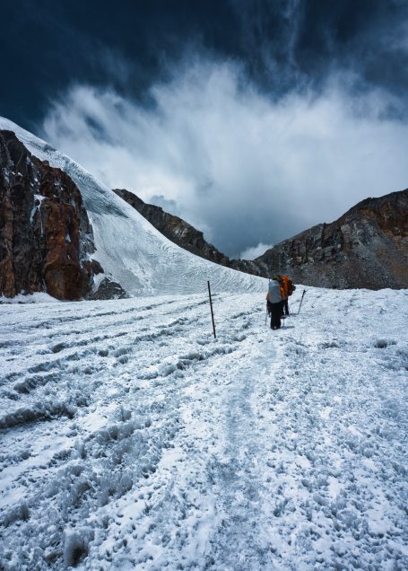 Winterlandschaft mit schneebedecktem Boden und einer Person, die in der Ferne geht.