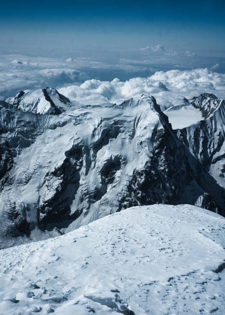 Schneebedeckte Berglandschaft mit schroffen Gipfeln und weitem Himmel.