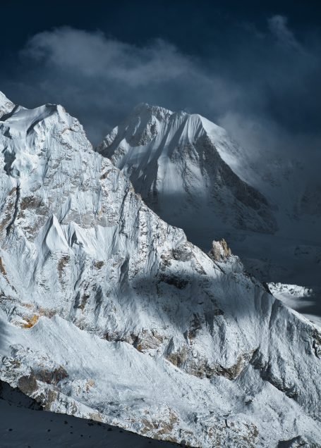 Schneebedeckte Berglandschaft mit dramatischen Wolken und Schatten.