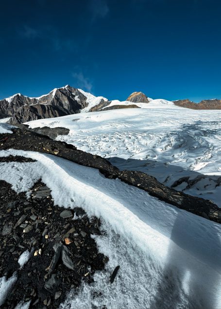 Schneebedeckte Berglandschaft mit blauen Himmel und Gletscher im Hintergrund.