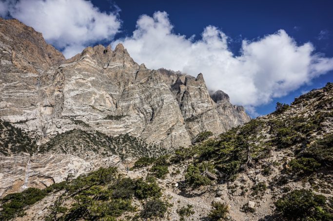 Majestätische Berglandschaft mit hohen Felsen und weiß bewölktem Himmel.