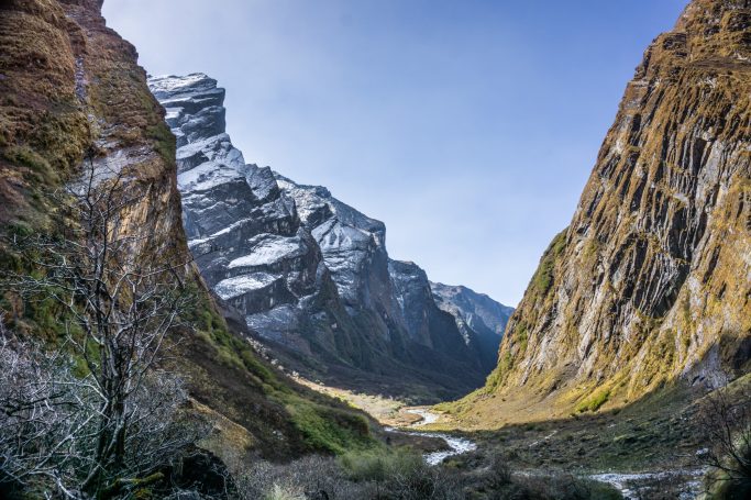 Bergige Landschaft mit schneebedeckten Gipfeln und einem grünen Tal dazwischen.
