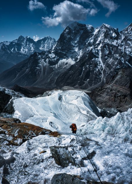 Bergsteiger auf einem gefrorenen Hang mit schneebedeckten Gipfeln im Hintergrund.