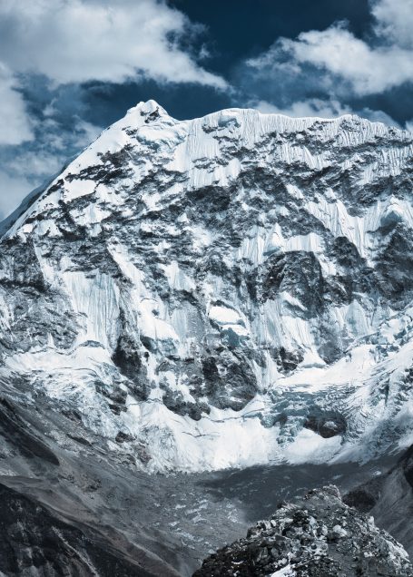 Hoher, schneebedeckter Berg unter einem blauen Himmel mit Wolken.