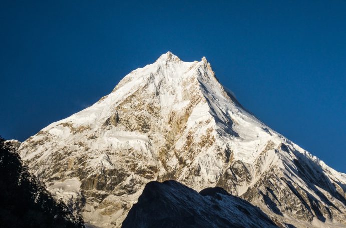 Hoher, schneebedeckter Berg unter klarem blauen Himmel.