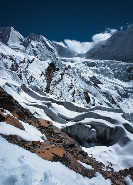 Berglandschaft mit schneebedeckten Gletschern und felsigen Formationen im Hintergrund.