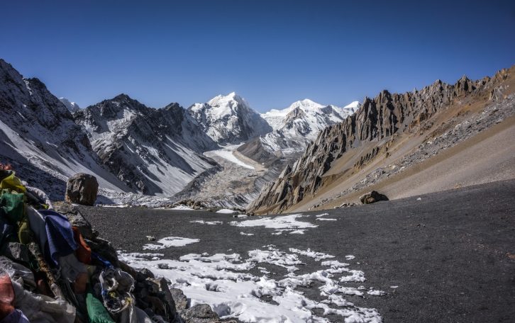 Berglandschaft mit schneebedeckten Gipfeln und steilen Felsen im Vordergrund.