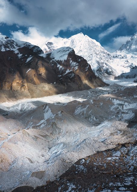Hochgebirgslandschaft mit schneebedeckten Gipfeln und glitzerndem Gletscher.