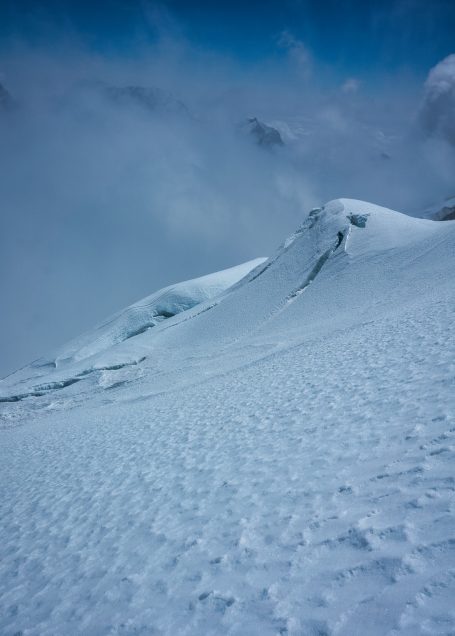 Schneebedeckte Berglandschaft mit Wolken und klar blauem Himmel.